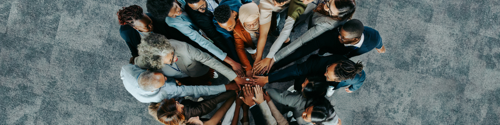 A diverse professional team joining hands in a circle.
