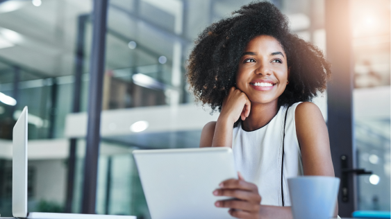 Woman with curly hair at a desk smilling.