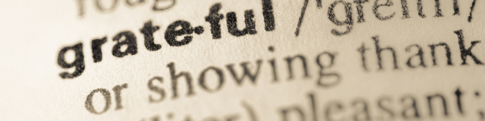 Close-up of the word "grateful" defined in a dictionary.